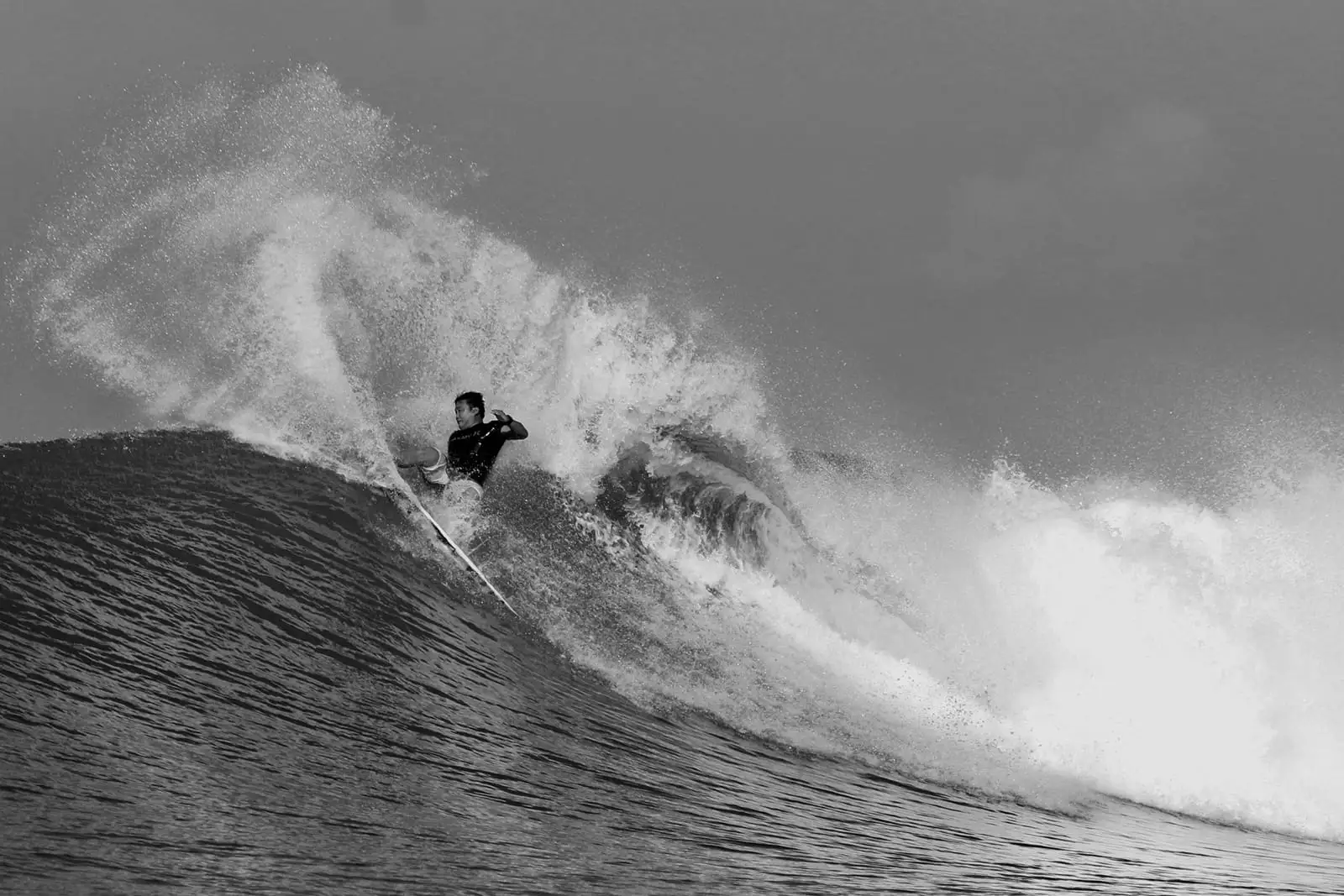 Justin Buu’lolo carving off the top of a wave, throwing spray
