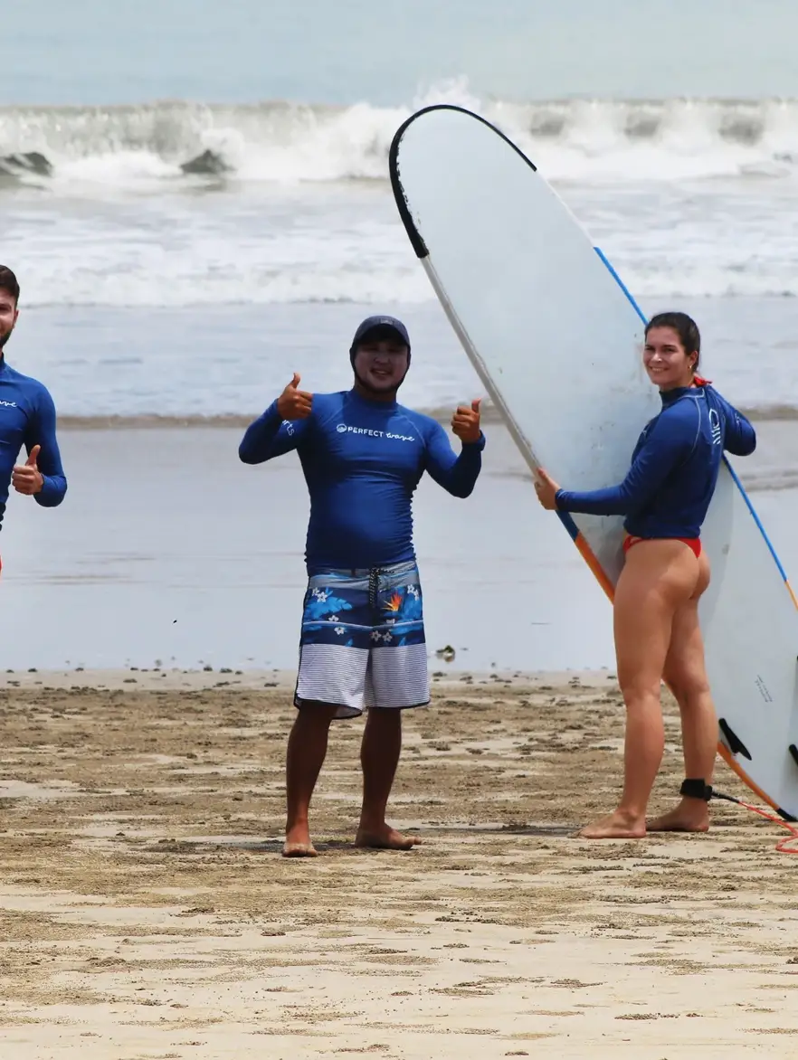 Justin Buu’lolo on the beach with two surfers holding their boards after a lesson in Bali